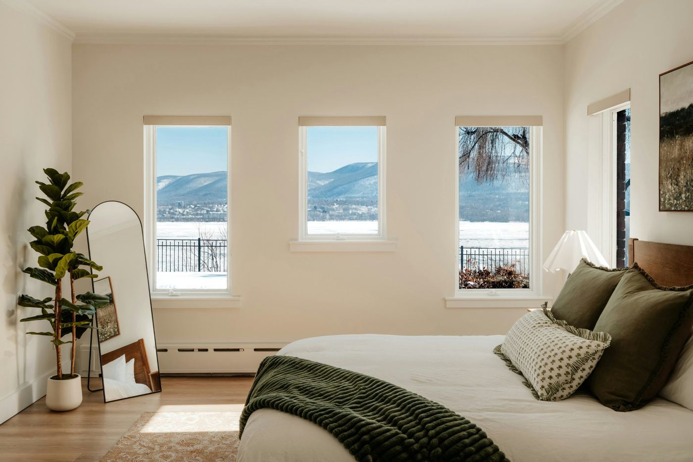 Bright bedroom with windows looking out on a snowy lake and hills